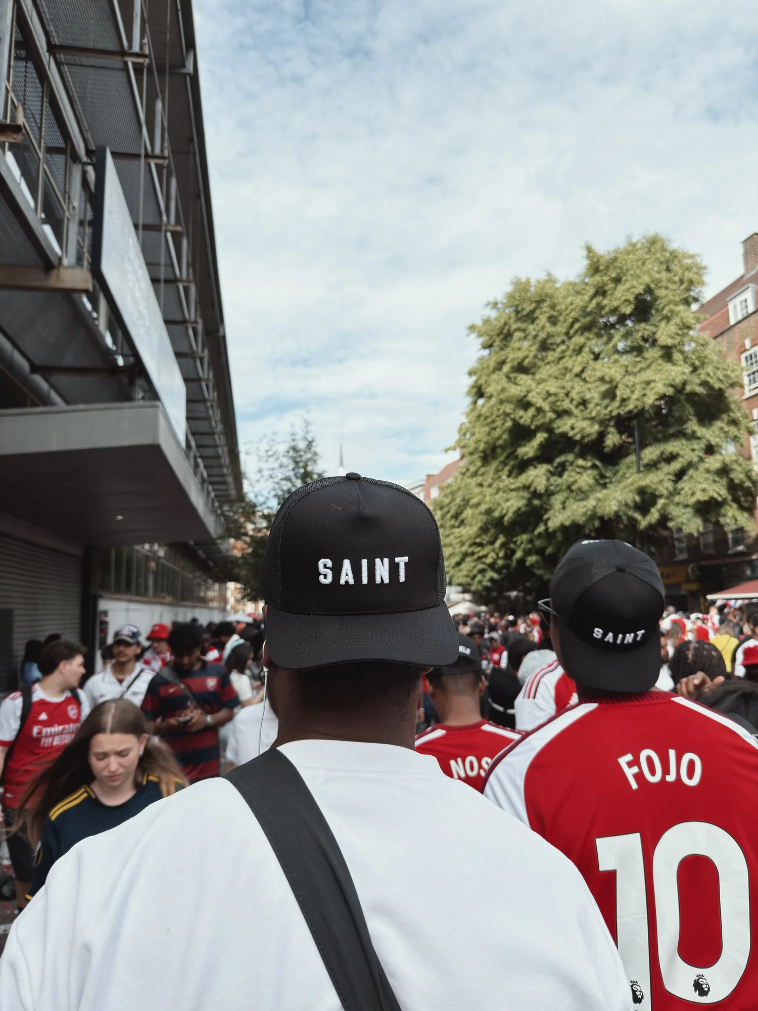Two people in SAINT caps in a matchday crowd